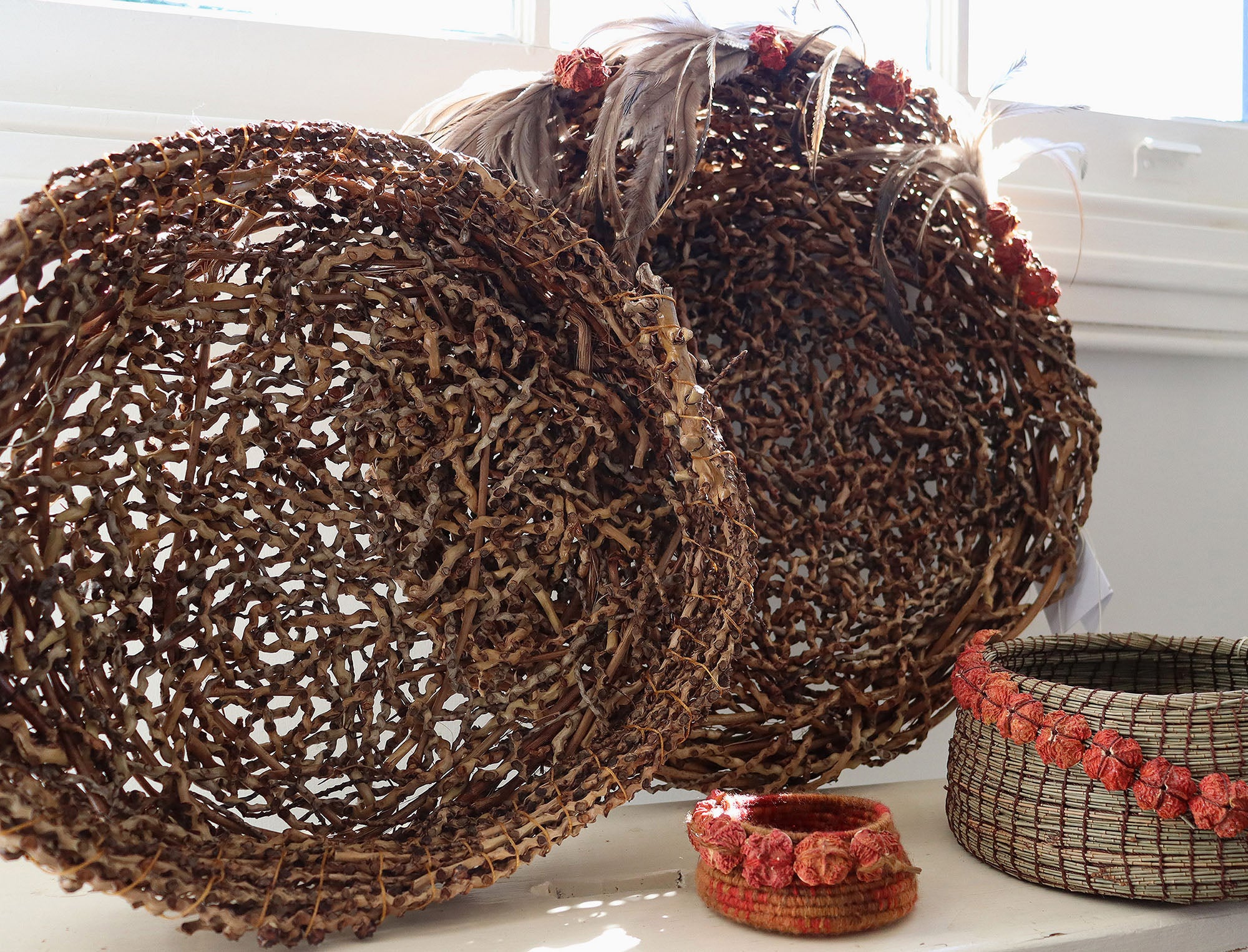 Decorative woven baskets with floral accents on a white surface